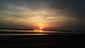 Atardecer sobre una superficie acuática tranquila con una costa lejana.