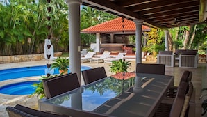 A covered outdoor area with a pool, lounge chairs, and a dining table. - Villa Alondra by Casa de Campo Resort & Villas (La Romana)