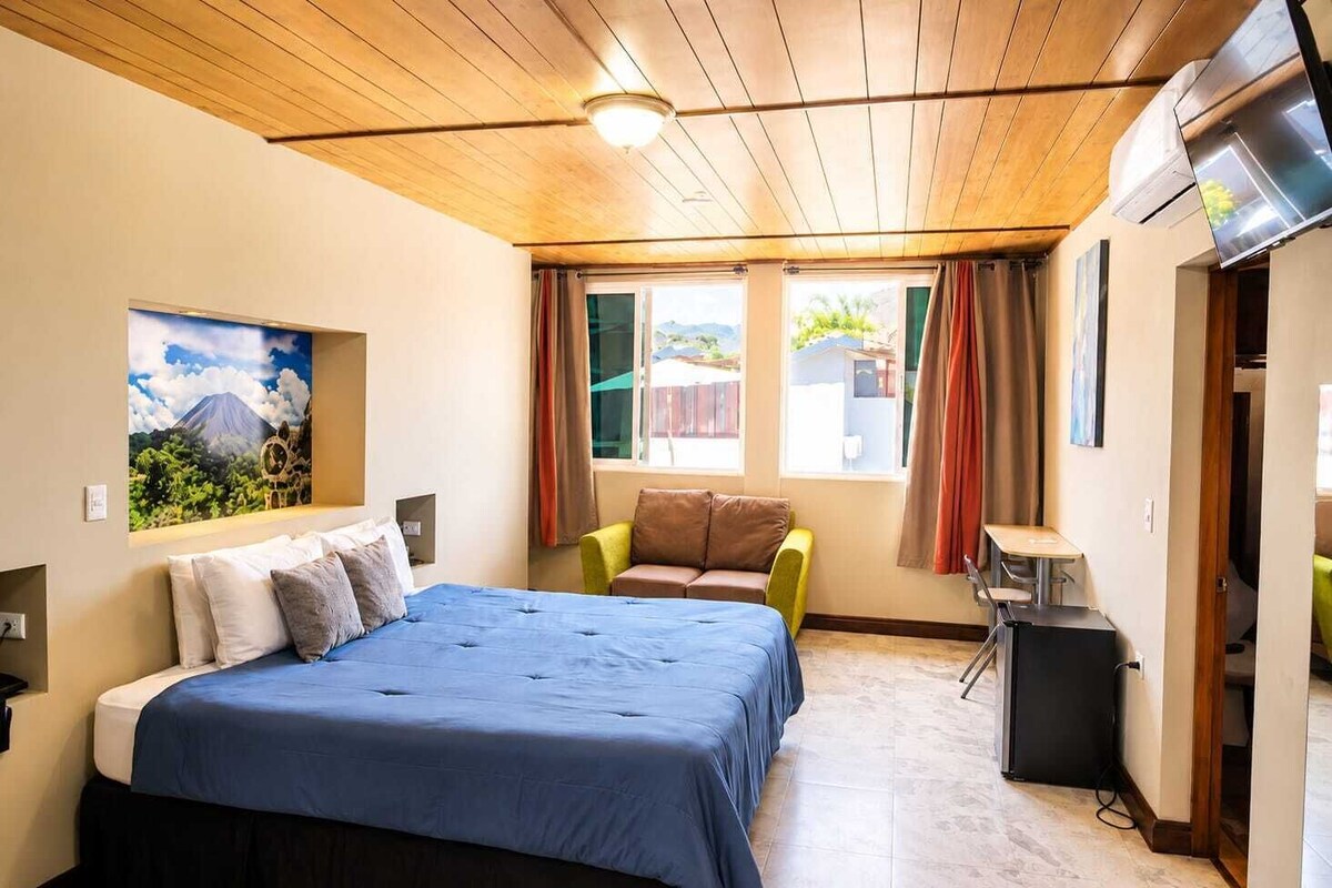 Ein Schlafzimmer mit Bett, Sofa, Schreibtisch und Fernseher.