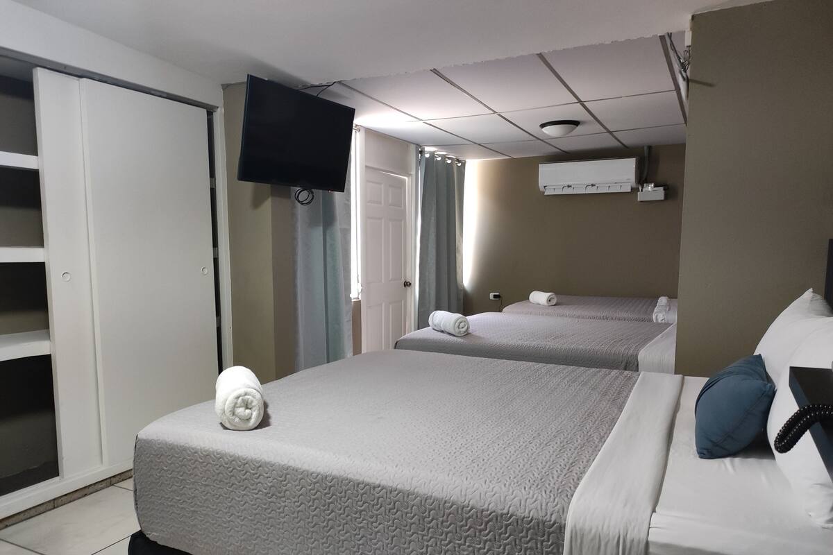 Habitación de hotel con dos camas, televisor, aire acondicionado y una puerta.