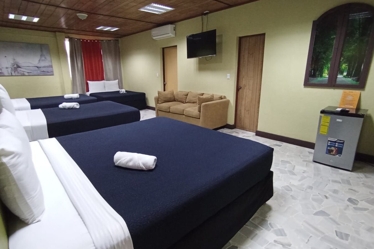 Une chambre d’hôtel avec deux lits, un canapé, une télévision et un petit réfrigérateur.