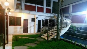 Ein mehrgeschossiges Gebäude mit Treppe, kleinem Pool und gepflegtem Rasen.