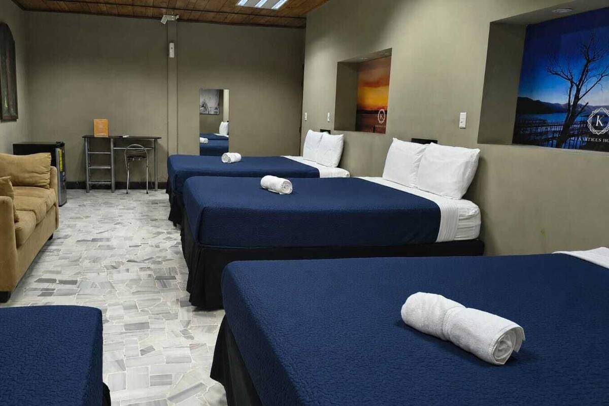 Habitación de hotel con dos camas, un sofá, una mesita y un espejo.