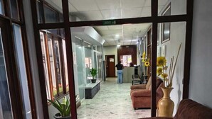 Eine Lobby mit Steinboden, einem braunen Sofa und einem Empfangstresen.