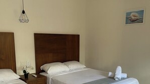 A hotel room with two beds, a nightstand with a remote control, a potted plant, and a wall-mounted air conditioner. - Hotel San Julio (Celestún)