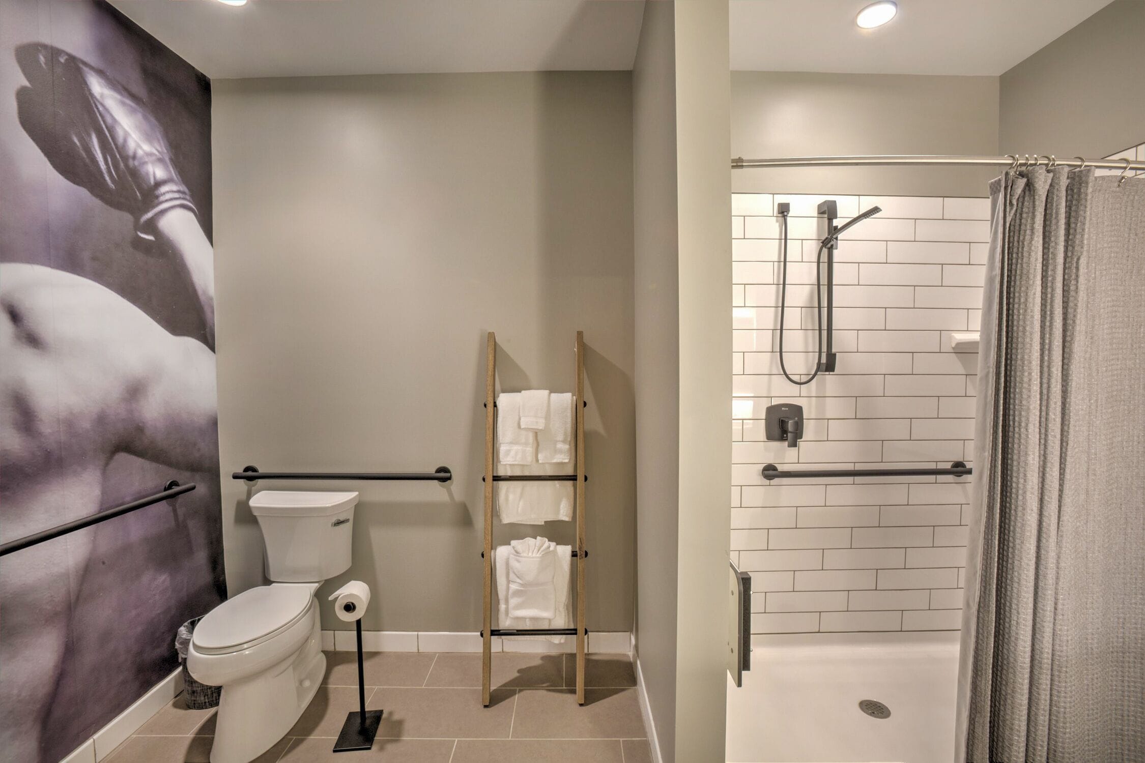 A bathroom with a toilet, a towel rack, a shower with a glass door, and a wall-mounted hand dryer.