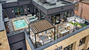 A rooftop with a pool, outdoor seating, and a bar area.
