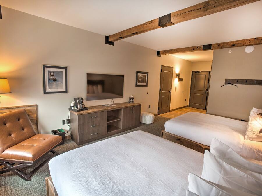 Een hotelkamer met een bed, een bank, een televisie, een houten kast en een deur.
