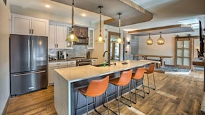 A modern kitchen with a central island, stainless steel appliances, and pendant lighting.