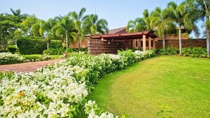 A well-maintained garden with a pathway leading to a building with a red roof and stone walls.