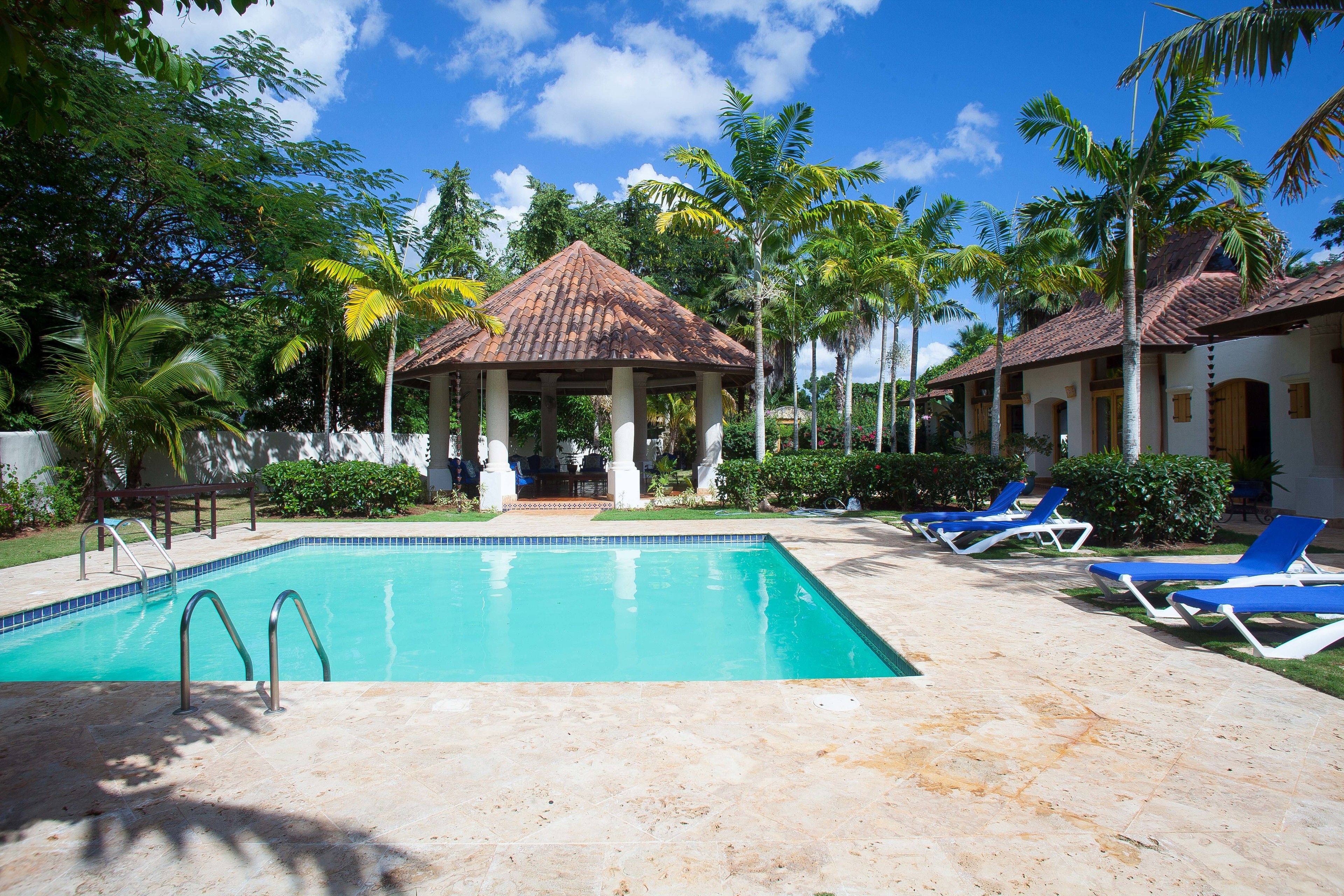 A swimming pool with lounge chairs and a gazebo.