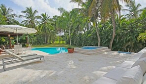 A pool area with a sun lounger, a covered seating area, and a small pool.