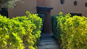 A pathway leading to a building with a modern design, surrounded by well-maintained greenery. - Locanda degli Scrittori (Agrigento)
