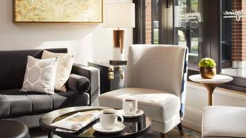 A modern living room with a grey sofa, a beige armchair, and a coffee table with two cups of coffee.