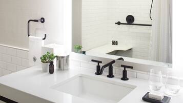 A modern bathroom with a white sink, black faucets, and a mirror reflecting the room.