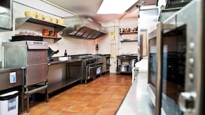 Une cuisine professionnelle équipée d’appareils en acier inoxydable, dotée d’un revêtement de sol carrelé et d’étagères murales.