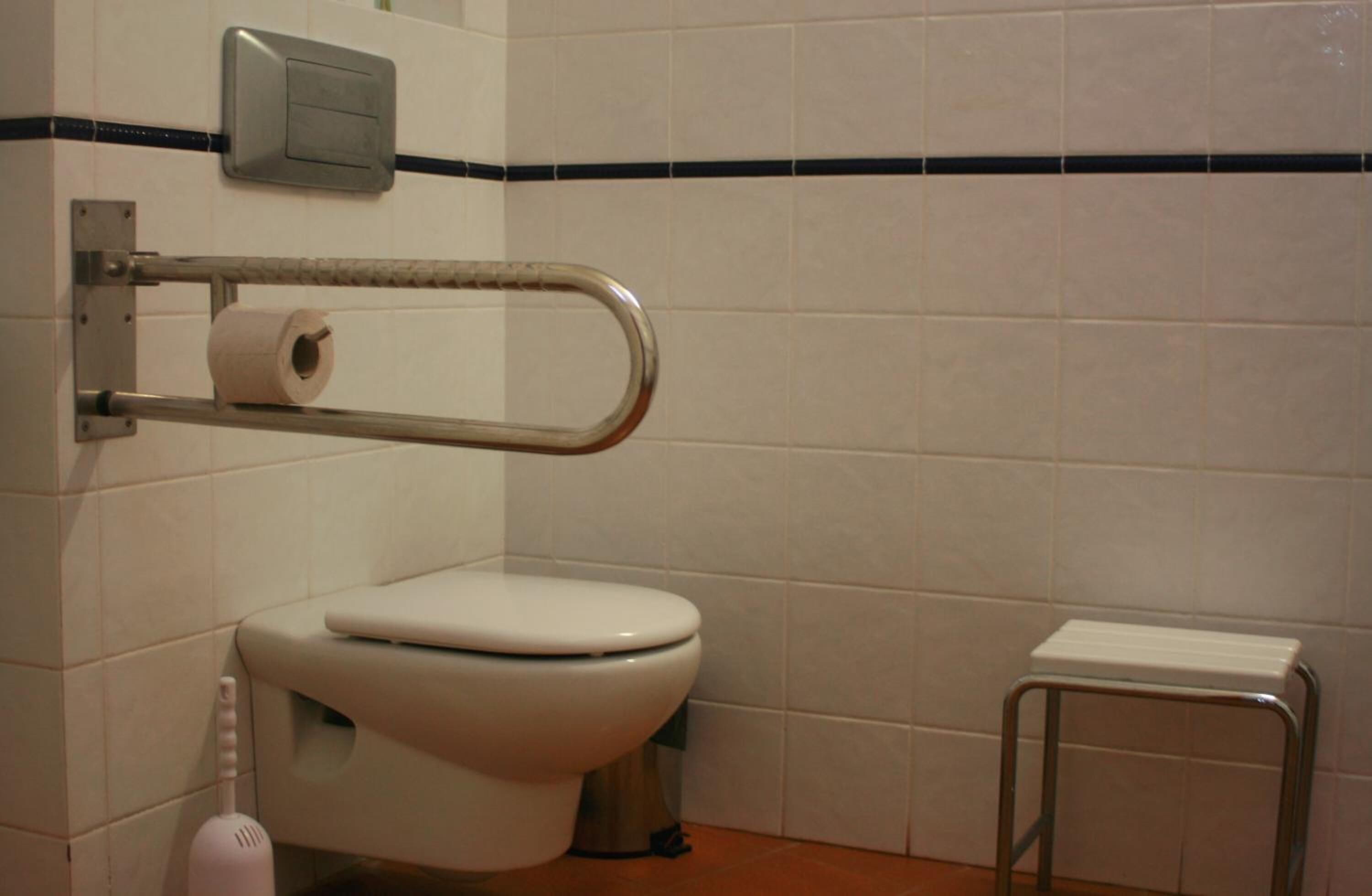 A standard bathroom with a toilet, a hand dryer, and a small stool.