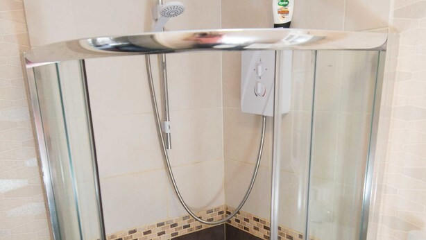 A glass-enclosed shower stall with a tiled floor and a showerhead. - Snooze Apartments Flat 52 (Bradford)