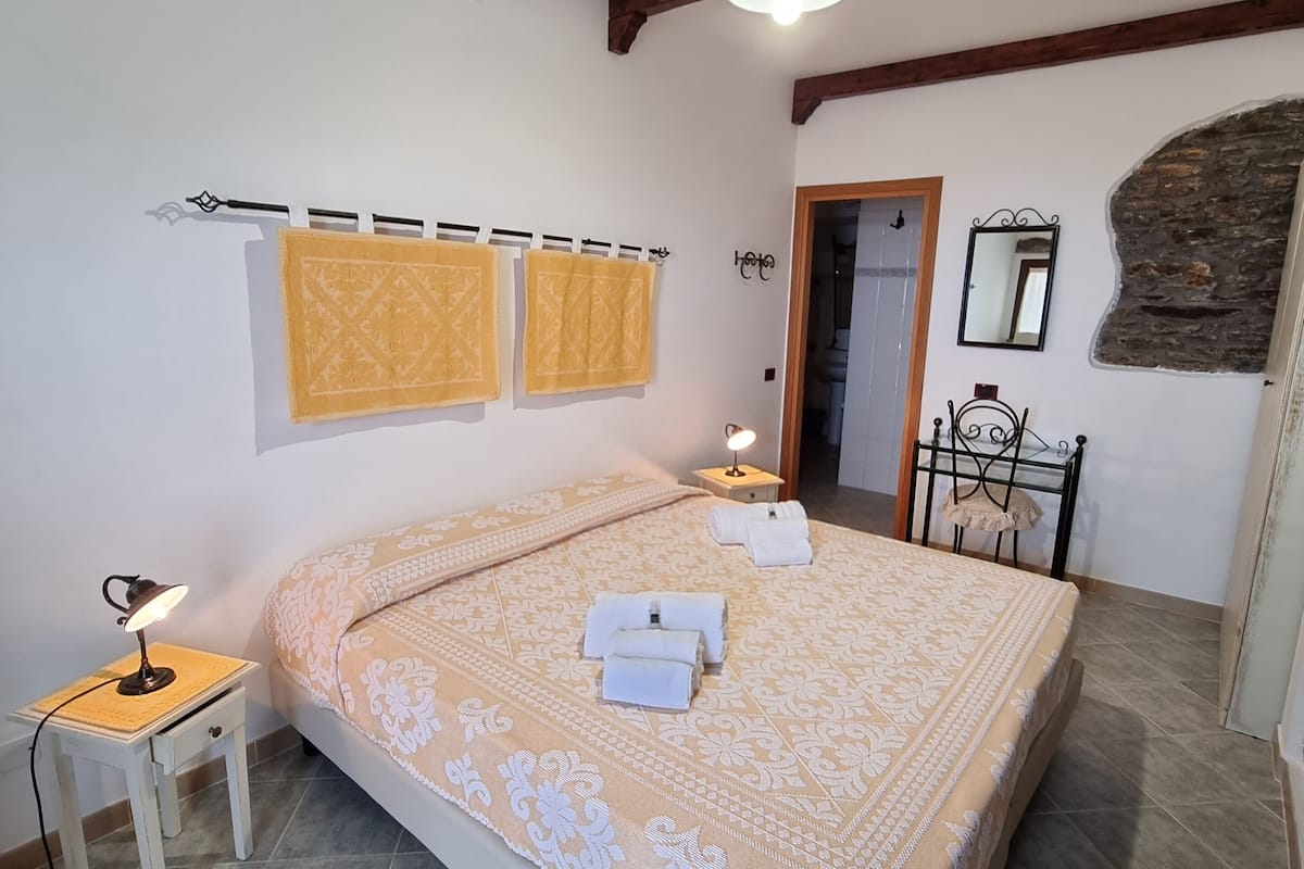 Un dormitorio con una cama grande, dos toallas, una lámpara de noche y una mesita.