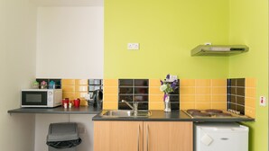 A compact kitchen with a microwave, toaster, sink, and a small refrigerator.