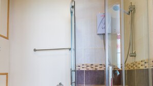 A bathroom with a glass-enclosed shower, a toilet, and a towel on the floor.