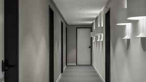 Un couloir moderne avec des luminaires encastrés, un sol recouvert de moquette et une porte au fond.