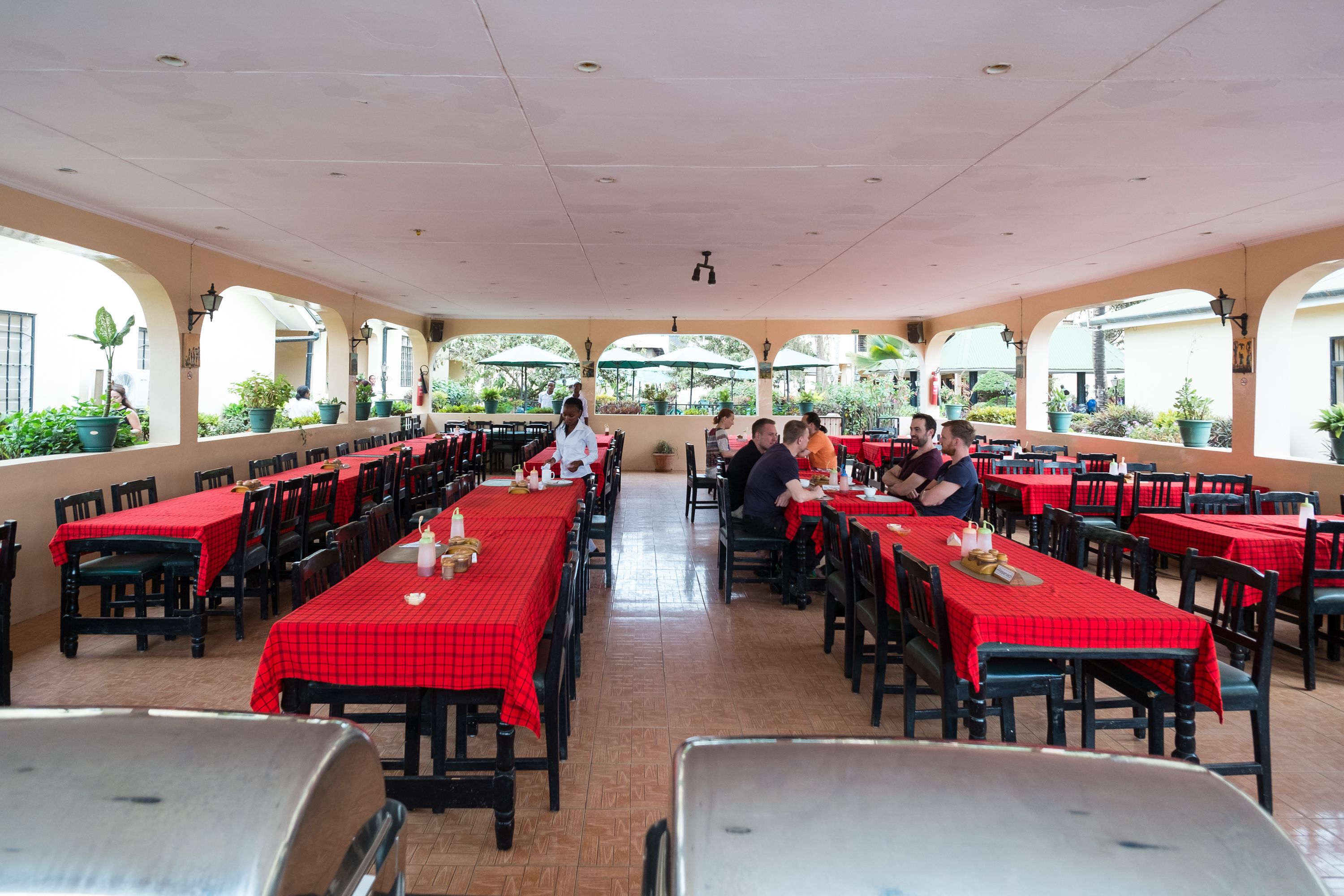 A restaurant with red checkered tablecloths, black chairs, and a tiled floor.
