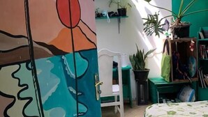 Ein Schlafzimmer mit einem Bett, einem farbenfrohen abstrakten Gemälde und einer grünen Wand.