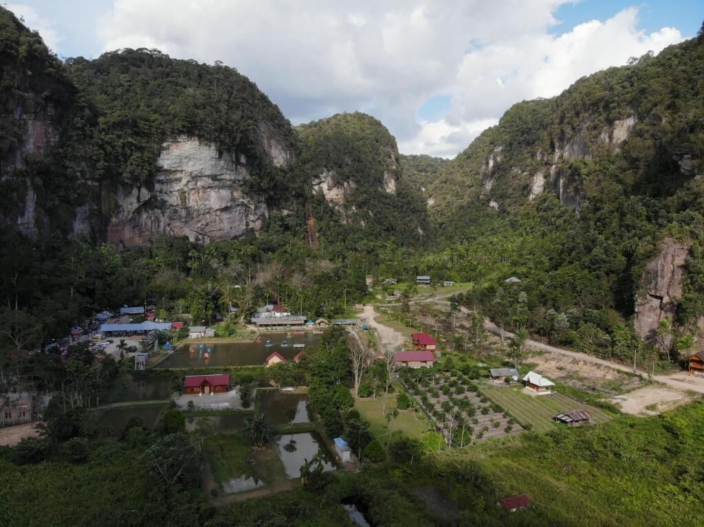 A valley with a small settlement, including houses and a pond.