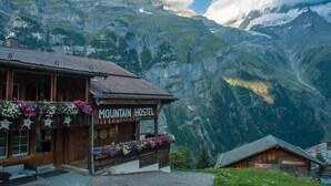 A mountain hostel with a wooden facade, flower boxes, and a sign indicating it offers billiards and laundry services. - Mountain Hostel Gimmelwald (Lauterbrunnen)