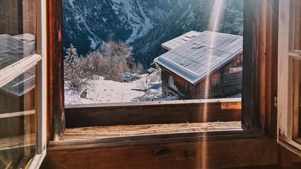 A wooden cabin with a view of snow-covered mountains through an open window. - Mountain Hostel Gimmelwald (Lauterbrunnen)