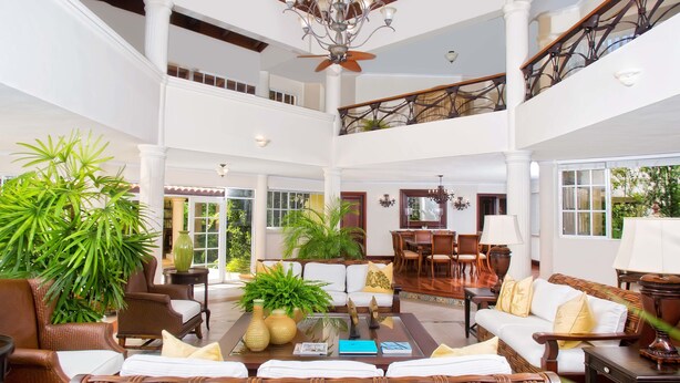 A spacious lobby with a high ceiling, a chandelier, and a dining area with wooden furniture. - Villas Los Pinos by Casa de Campo Resort & Villas (La Romana)
