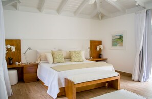 A bedroom with a large bed, wooden headboard, bedside tables with lamps, and a painting on the wall.