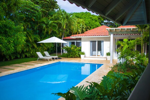 A swimming pool with lounge chairs and a covered patio area.