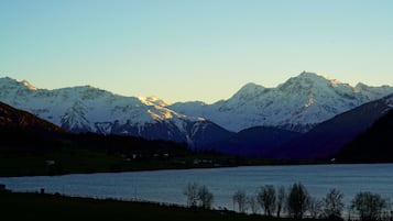 A mountain landscape with snow-capped peaks and a calm lake in the foreground.