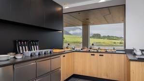 Una cocina moderna con un amplio ventanal que ofrece vistas a un paisaje verde y montañas.