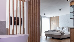 Un dormitorio moderno con una cama grande, un separador de madera, una pared de mármol y un televisor integrado.