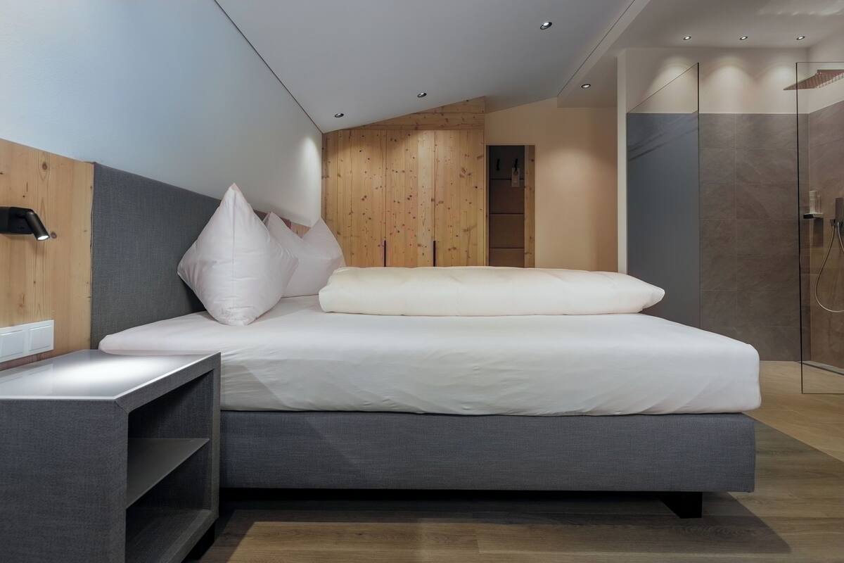 Ein modernes Schlafzimmer mit Bett, Nachttischen und einer Wand aus Holzverkleidung.