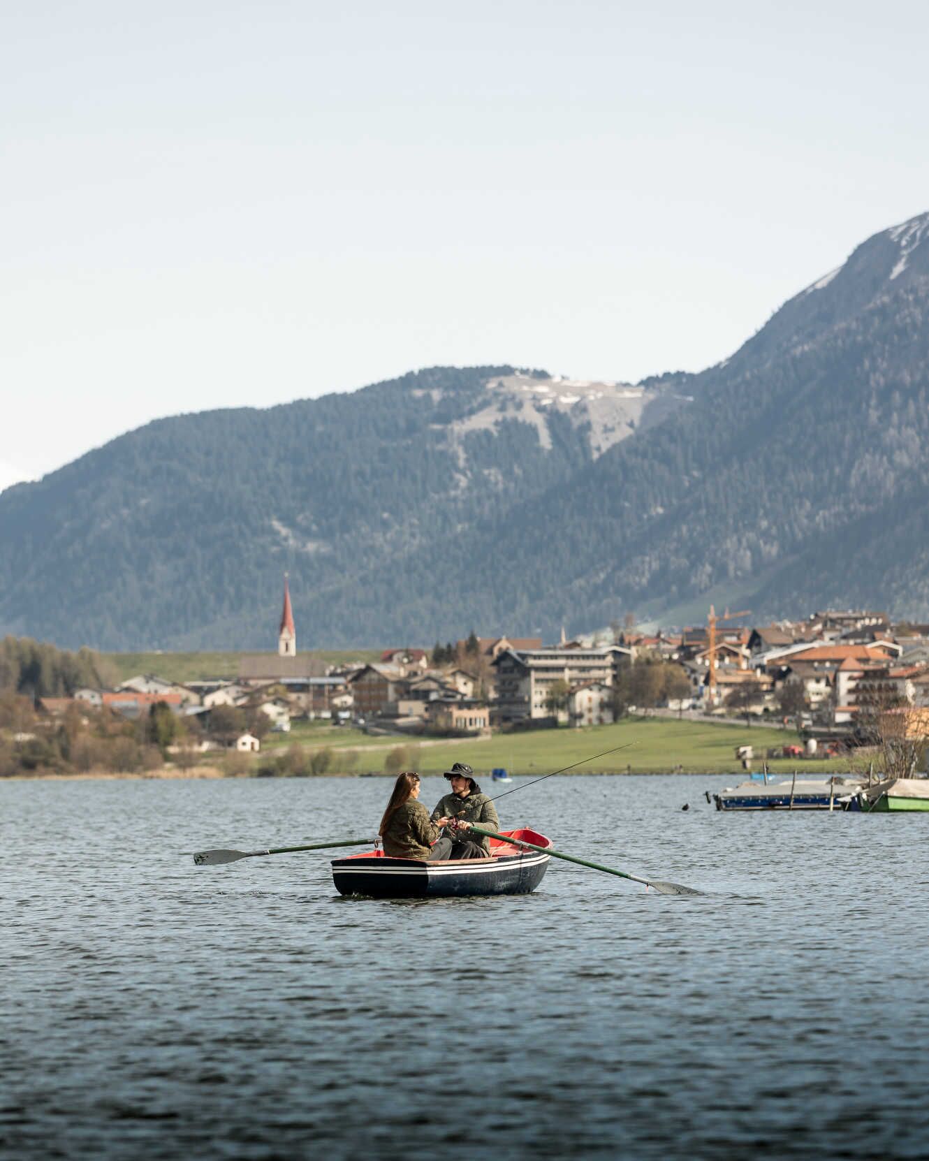 A small rowboat on a lake with a mountainous backdrop.