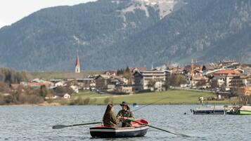 A small rowboat on a lake with a mountainous backdrop.