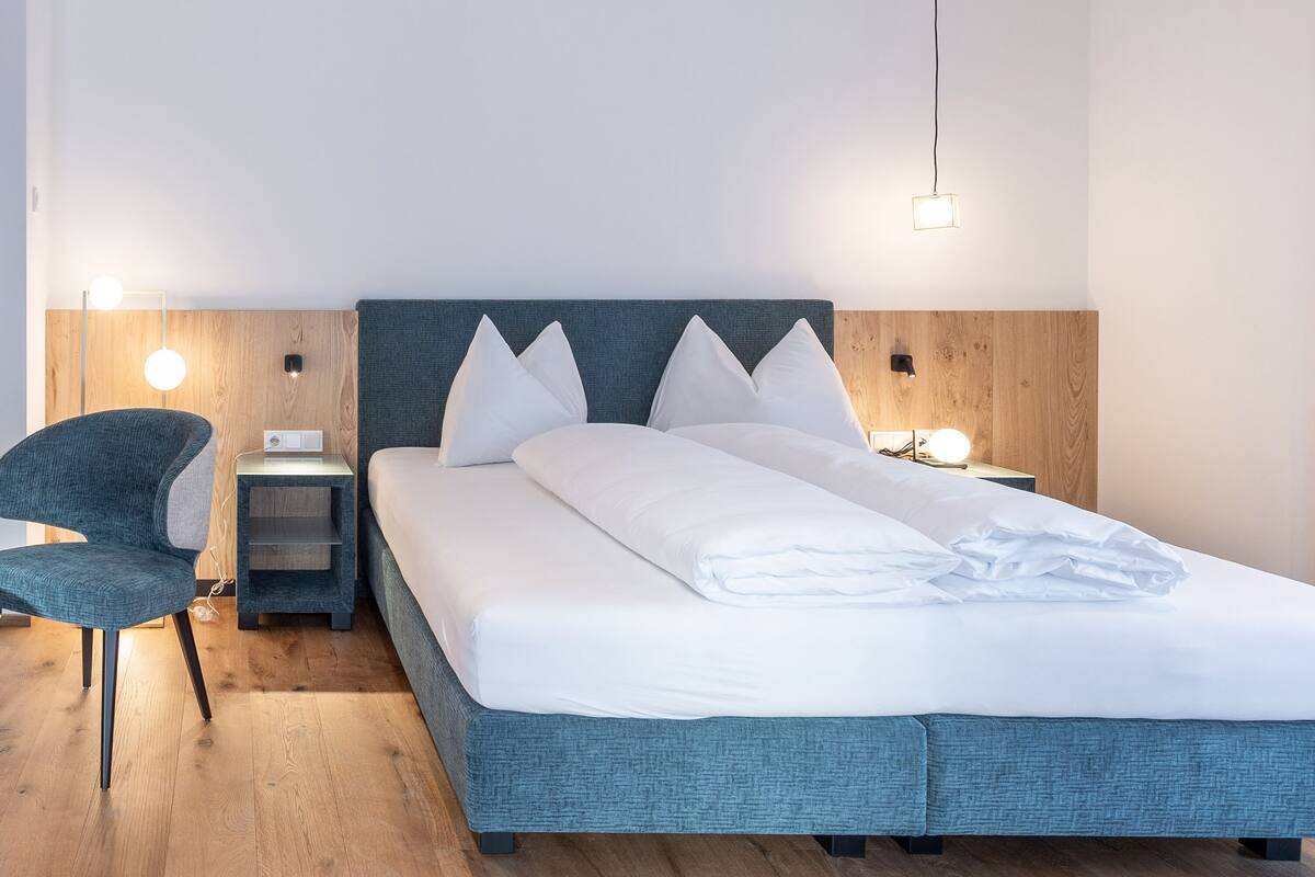 Ein modernes Schlafzimmer mit einem großen Bett, einem Sessel und Nachttischen.