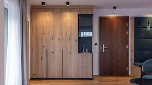 Una habitación moderna con un armario de madera, una puerta oscura y una pequeña mesa.