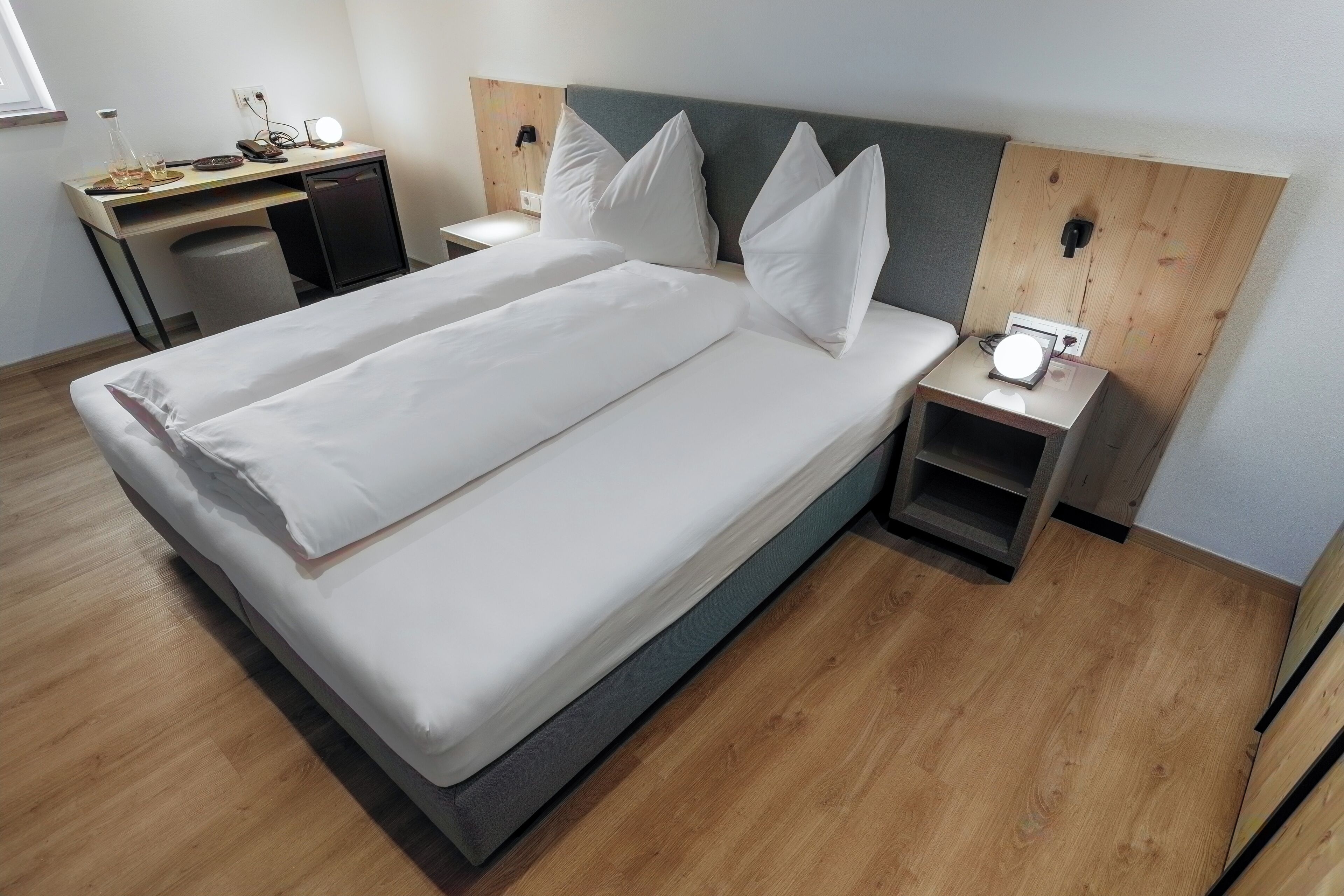 A hotel room with a bed, bedside tables, a desk, and a chair.