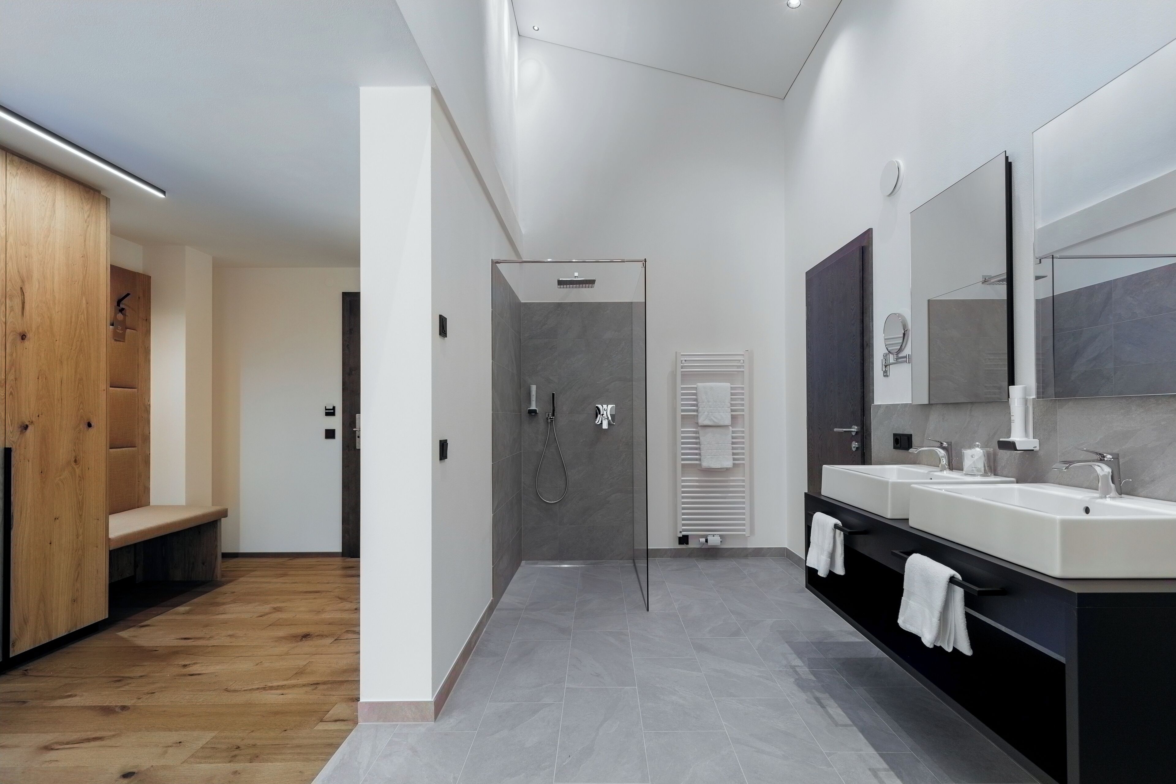 A modern bathroom with a shower, two sinks, and a vanity.