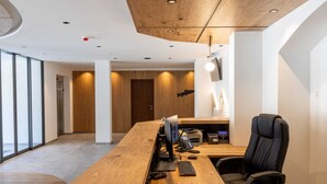 Un espacio de oficina moderno con un escritorio de madera, sillas de oficina negras y un amplio ventanal que proporciona luz natural.
