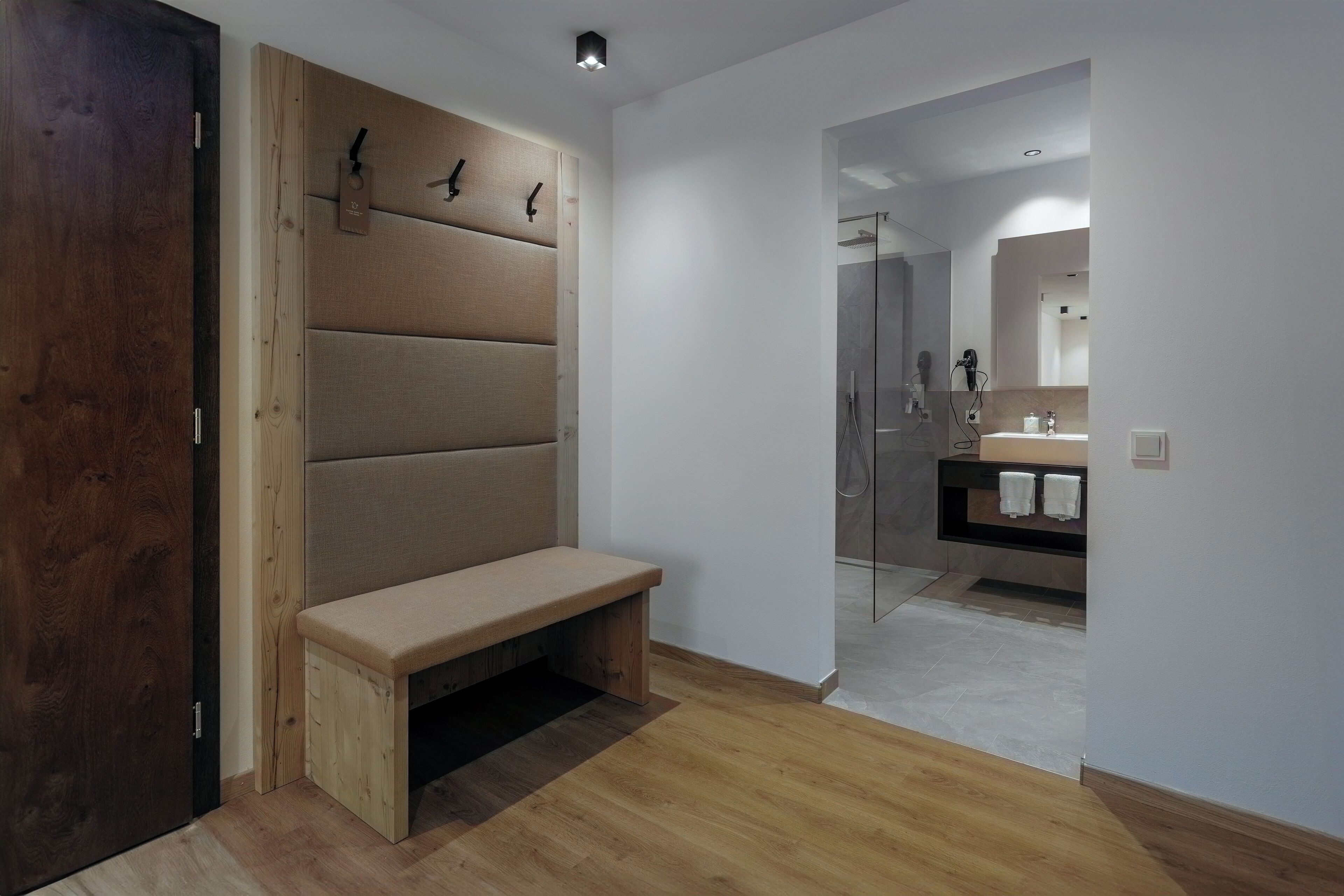 A modern bathroom with a bench, a glass shower enclosure, and a vanity with a mirror.