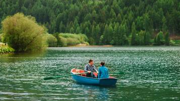 Two people in a small boat on a calm lake surrounded by dense forest.