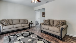 A living room with two sofas, a patterned rug, and a ceiling fan.