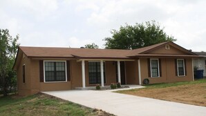 A single-story house with a front porch, a garage, and a well-maintained lawn.