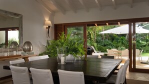 A dining area with a large table, white chairs, and potted plants. - Claro de Luna by Casa de Campo Resort & Villas (La Romana)